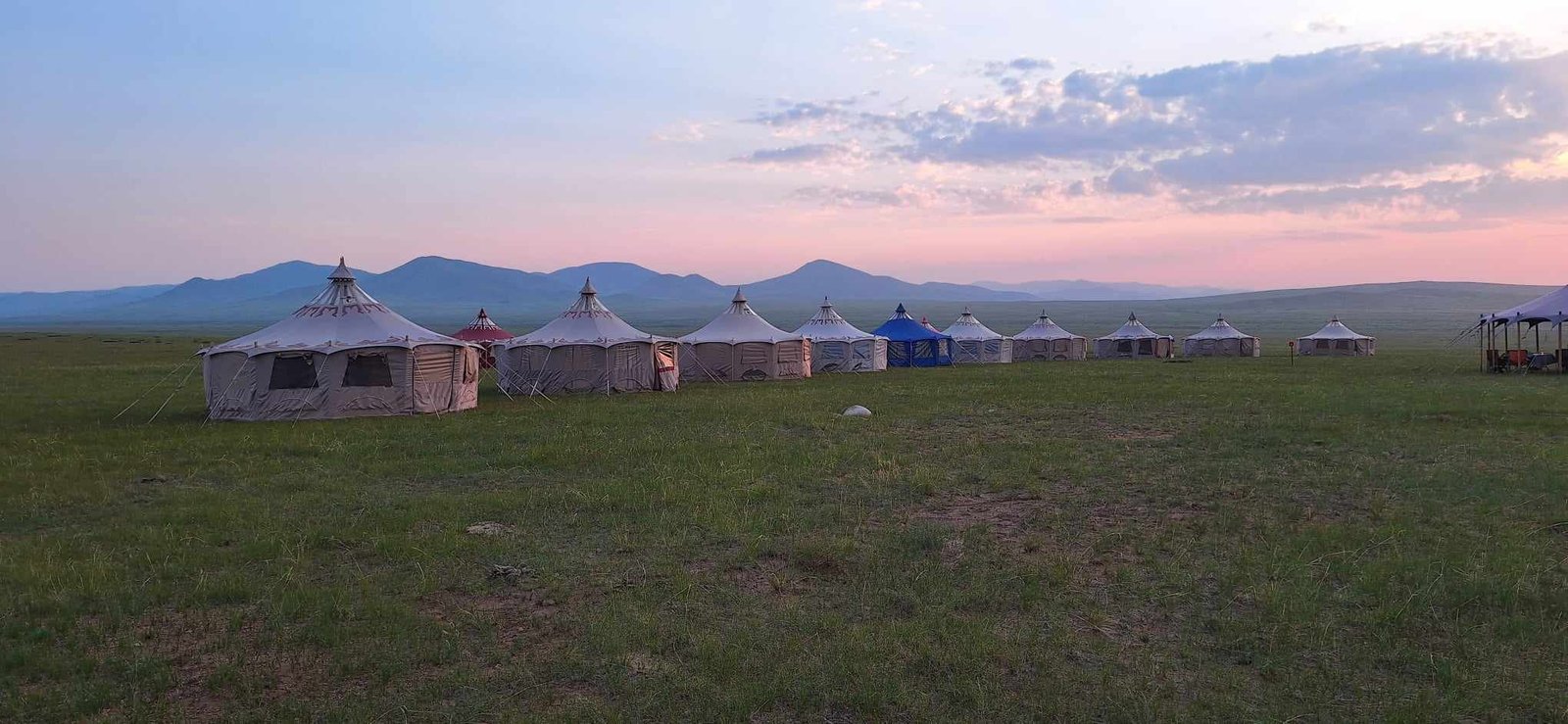 Ger camp at dusk with mountains behind