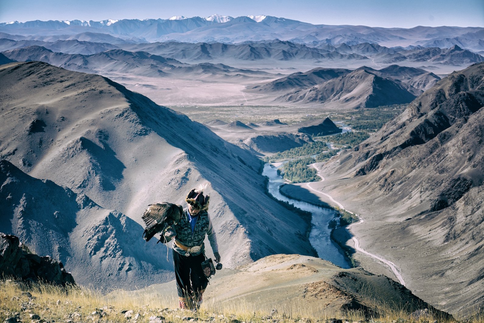 Eagle hunter on a rock as his golden eagle opens its wings