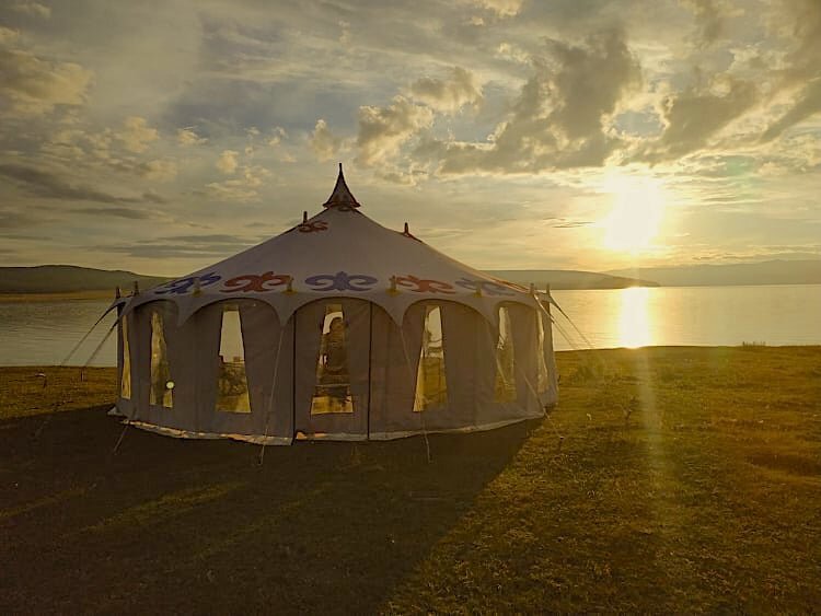 Seven metre mobile ger pitched by a lake at sunset