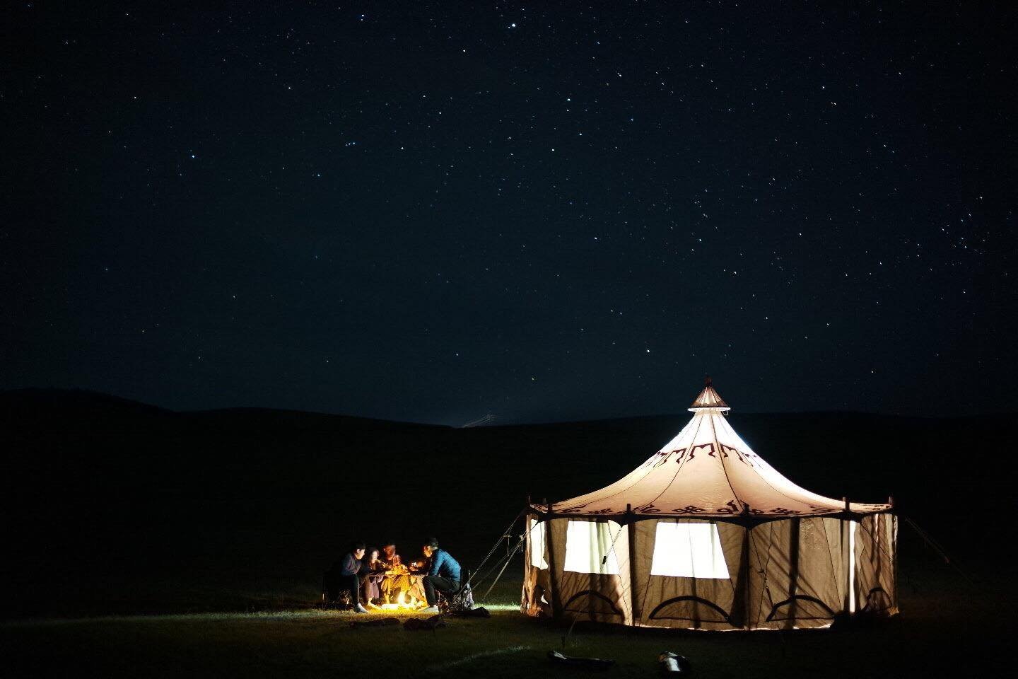Glamping tent lit from within under a night sky full of stars