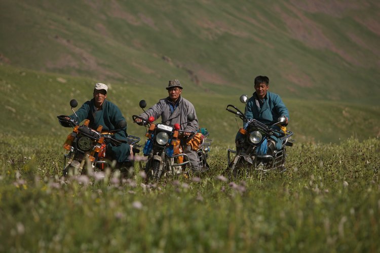 Rider taking an ATV up a bare hillside ridge