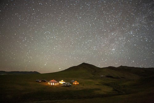 Mobile ger camp lit from within under a sky full of stars